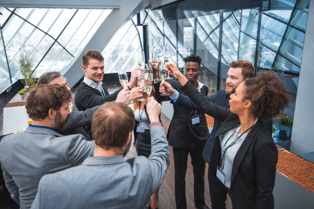A diverse team erupts in celebration with champagne toasts, high fives, and laughter in a modern office setting. This image captures the triumphant business  spirit of a team achieving success through collaboration and perseverance.